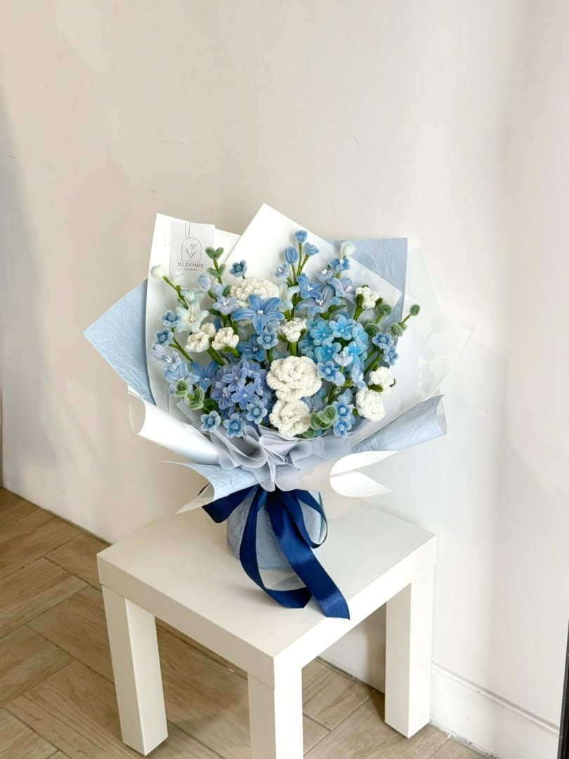 Blue and white chenille stem flowers wrapped in a pale blue bouquet