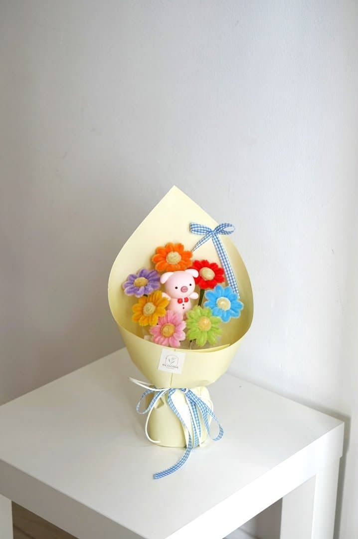 Small colourful handmade flower bouquet with a pink figure and blue gingham ribbon