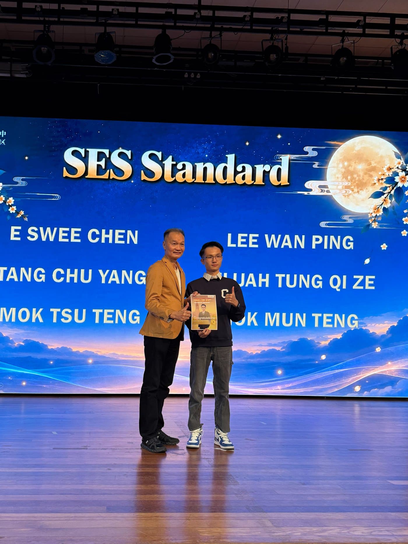 Elijah holding his certificate on stage at the SES Standard award presentation